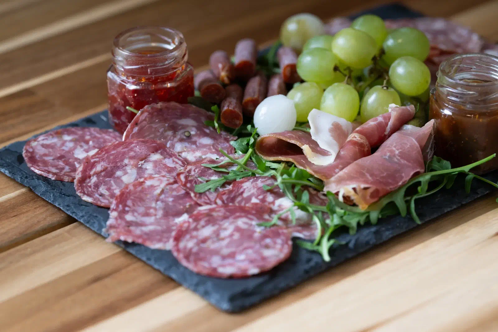 A slate of cured meats, cheese, grapes and chutney