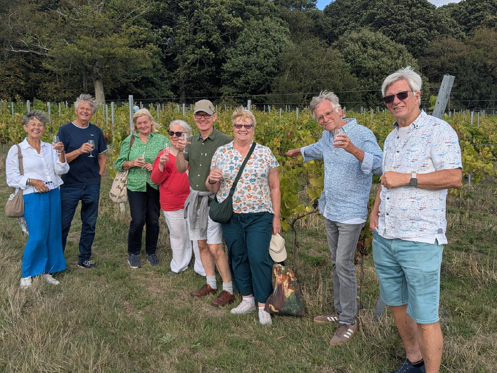 A group of eight guests standing together in front of the vines